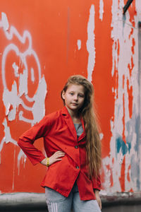 Portrait of smiling woman standing against red wall