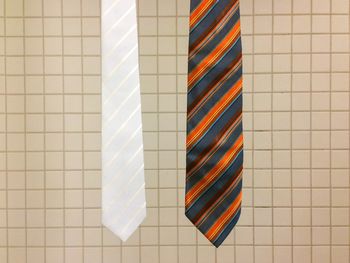 Close-up of neckties hanging against tiled wall