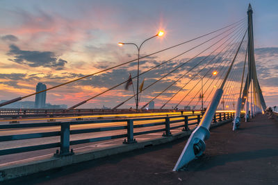 Light trails on illuminated rama viii bridge against cloudy sky at dusk in city