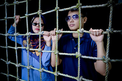 Portrait of young woman looking through chainlink fence