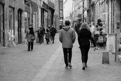 Rear view of people walking on street in city