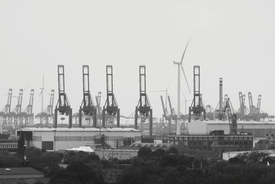 Cranes at commercial dock against clear sky