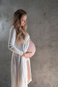 Beautiful young woman standing against wall