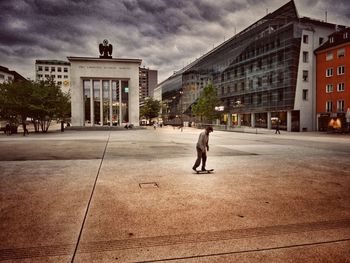 Full length of man walking on street against buildings in city