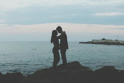 Couple kissing on sea against sky