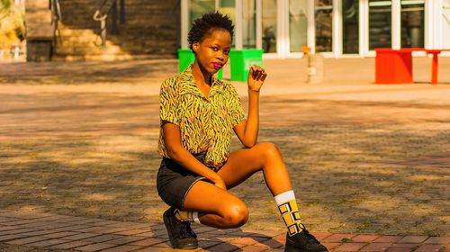 Portrait of young woman crouching on street