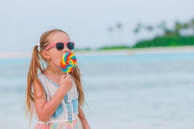 Young woman wearing sunglasses while standing at beach