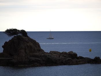 Sailboat on rock by sea against sky