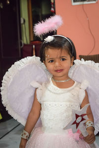 Portrait of innocent girl wearing angel costume at home