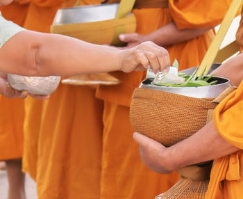 Midsection of man holding orange while standing at temple