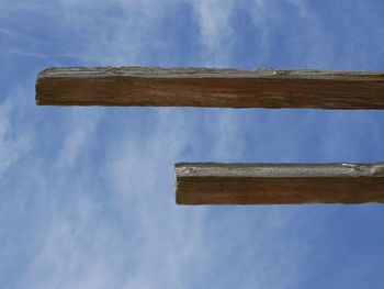 Low angle view of wooden planks against cloudy blue sky