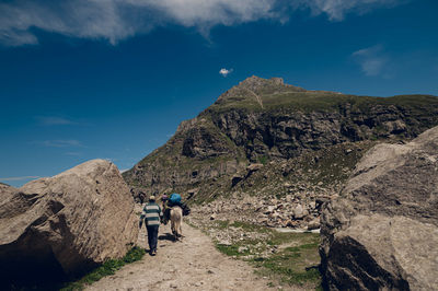 Rear view of man walking on mountain against sky
