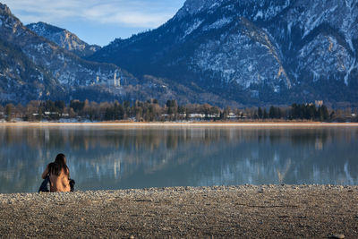 Rear view of woman looking at lake against mountains