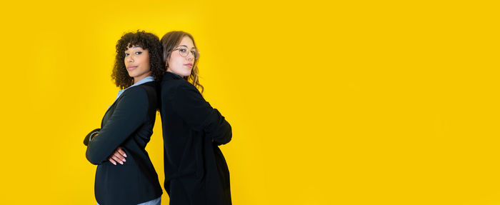 Portrait of woman standing against yellow background