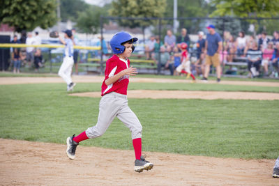Full length of boy running on ground while playing baseball