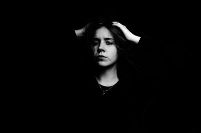 Portrait of young woman against black background