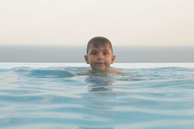 Portrait of boy swimming in infinity pool