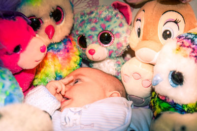 Cute baby boy with finger in mouth lying amidst toys