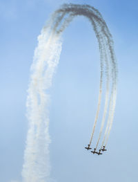 Low angle view of military airplanes performing airshow against sky