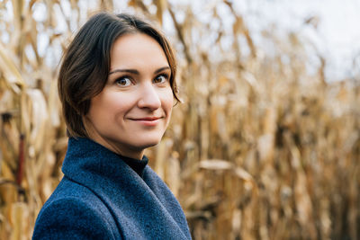 Portrait of attractive young woman in autumn coat in cornfield