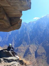 Side view of hiker sitting on cliff