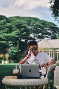 Young man using mobile phone while sitting on table