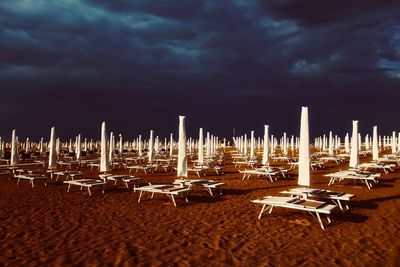 Lounge chairs on sand at beach against sky
