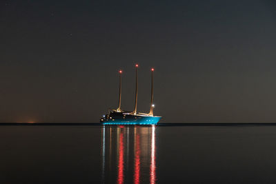 Illuminated lights on sea against sky at night