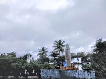 Low angle view of palm trees by building against sky