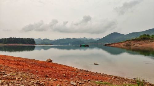 Scenic view of lake by mountains against sky