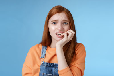 Portrait of smiling young woman against blue background