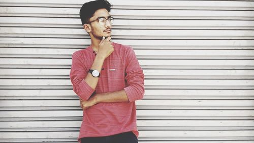 Thoughtful young man standing against shutter