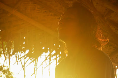 Low angle view of man looking away in hut during sunset