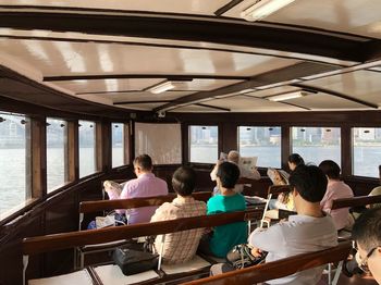 Rear view of people sitting in ferry on lake