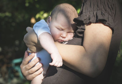 Midsection of mother carrying daughter outdoors