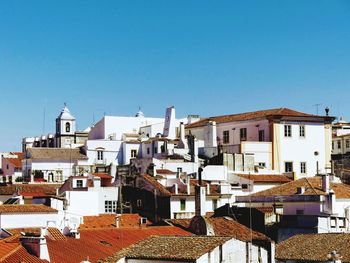 Buildings in city against clear blue sky