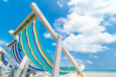 Low angle view of deckchair against cloudy sky