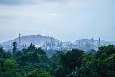 Heavy industrial view at oil and gas refinery plant surroundings by trees with cloudy weather.