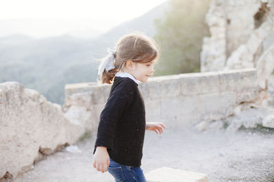 Full length of boy standing on mountain against sky