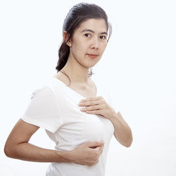 Portrait of woman with hands on chest standing against white background