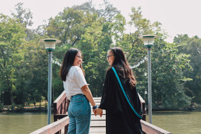 Rear view of girls holding hand standing on pier