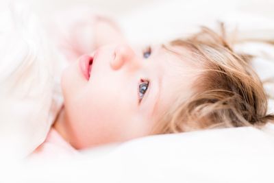 Close-up portrait of beautiful young woman lying on bed