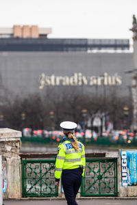 Rear view of man standing against wall in city