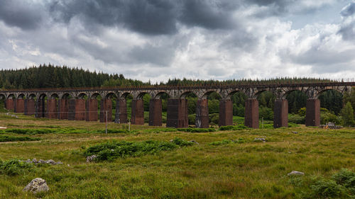 Arch bridge against cloudy sky