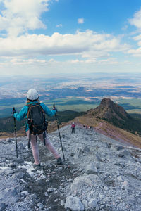 Rear view of woman walking on ridge against sky