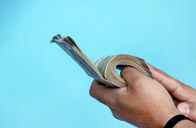 Cropped hand of person holding rope against clear blue sky