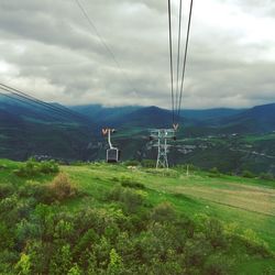 Overhead cable car on mountains against sky