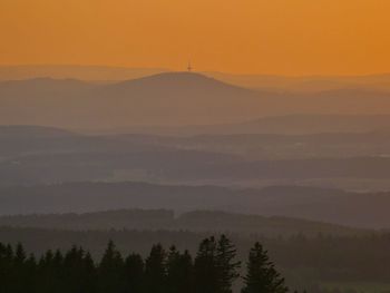 Scenic view of silhouette mountains against orange sky
