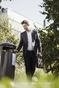 Businessman throwing garbage in bin at park