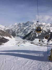 Ski lift over snowcapped mountains against sky